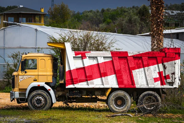 Dump truck with the image of the national flag of Georgia is parked against the background of the countryside. The concept of export-import, transportation, national delivery of goods