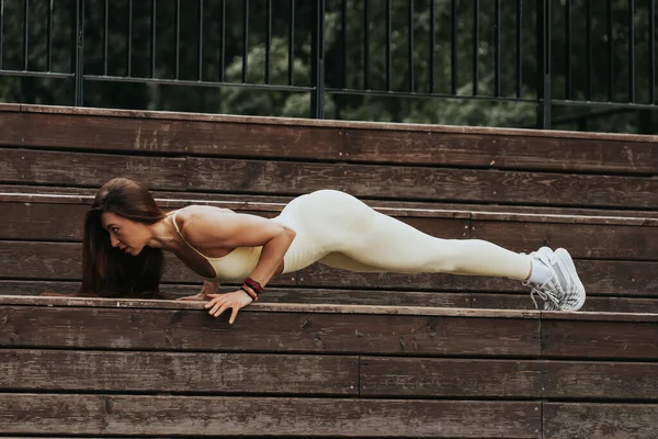 在城市公园里进行户外运动的年轻女子很合身 年轻美丽的女子穿着腿在公园里摆姿势 在公园里做枕头或瑜伽 — 图库照片