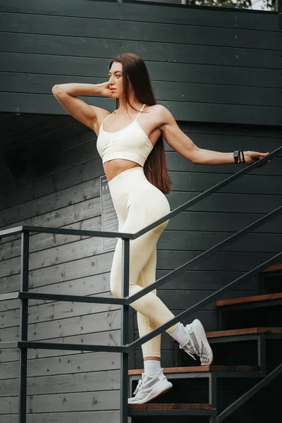 一个肌肉抽筋的女人的画像 在城市公园的楼梯上摆姿势的漂亮而活泼的女人 健美操概念 — 图库照片