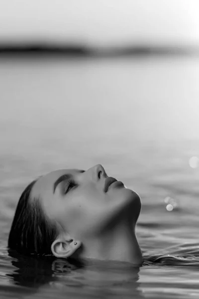 Portrait of a beautiful woman with wet hair  against the backdrop of the sea and sunset. fashionable stylish young woman