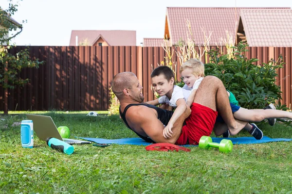 幸せな若いお父さんは緑の芝生の上で彼女の赤ちゃんと遊んでいます 幸せな家族の概念 父の日 父と息子は裏庭で休暇中に一緒に活動しています — ストック写真