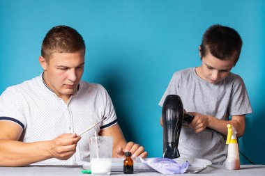 Baba ve oğul kimyasal deneyler yapıyorlar. Evde iyot ve nişastanın kimyasal reaksiyonunun sonucu olarak bukalemunun renginin değişimini gözlemliyorlar. Çocuk saç kurutma makinesiyle kuruyor.