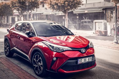 Alanya, Türkiye 12 Nisan 2021: Kırmızı Toyota C-HR bir binanın, dükkanların, ağaçların önüne park etti. 