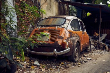 Eski, paslı, beyaz, turuncu eski araba enkazı eski bir caddede.