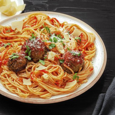 Klasik İtalyan spagettisi üzerine üç lezzetli domates soslu, taze maydanozla süslenmiş ve sade bir tabakta parmesan peyniri traş edilmiş makarna..