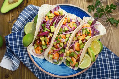 Avokado, lahana ve maydanozla kaplı ev yapımı karidesli tortilla dürümleri. Sokak yemekleri, Fiesta veya Cinco de Mayo kavramları için ideal..