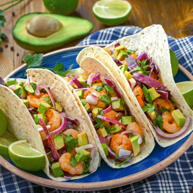 Avokado, lahana ve maydanozla kaplı ev yapımı karidesli tortilla dürümleri. Sokak yemekleri, Fiesta veya Cinco de Mayo kavramları için ideal..