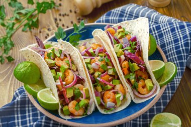 Sağlıklı deniz ürünleri tacoları karides, avokado ve lahana salatasını birleştirir. Malzemelerin dokularını ve canlı renklerini vurgulamak için başınızın üstünde fotoğraf çekilir..