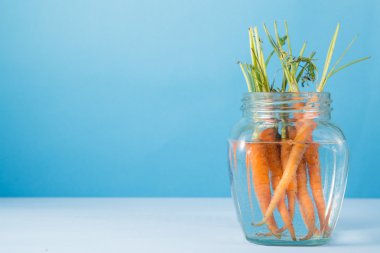 Bunch of fresh carrots in glass vase with water clipart
