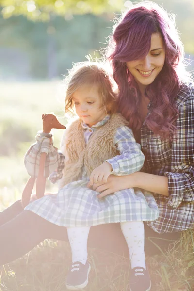 Moeder en dochter zittend op het veld in de zonsondergang — Stockfoto