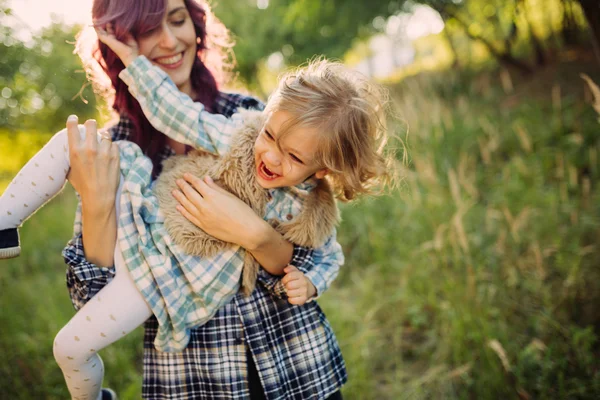 Moeder en dochter zittend op het veld in de zonsondergang — Stockfoto