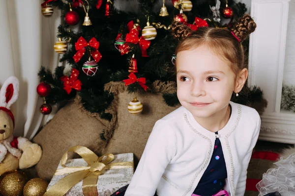 Menina feliz sentada na árvore de Natal — Fotografia de Stock
