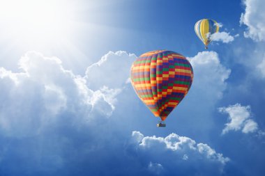 Hot air balloons flies in blue sky clipart