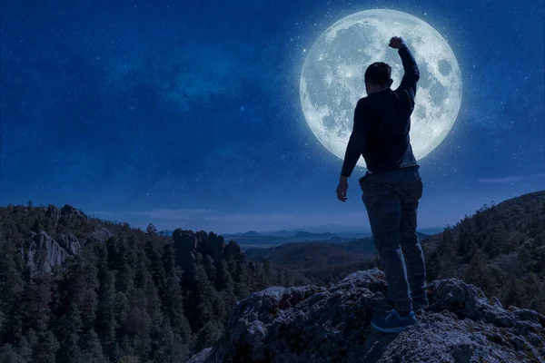 man on top of the mountain reaches for the moon