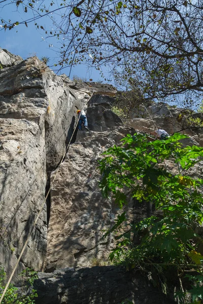 Adam Mavi Arka Planda Dikey Bir Kaya Duvarına Tırmanıyor — Stok fotoğraf