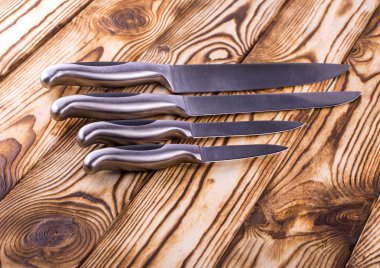 ahşap bir masa üzerinde parlak metal mutfak bıçak seti
