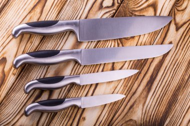 ahşap bir masa üzerinde parlak metal mutfak bıçak seti