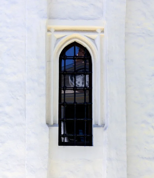 Window into the white wall of the monastery with reflection  the face  the clock — Stock Photo, Image