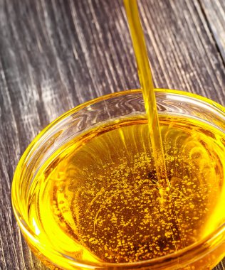 Dökülen yağ eski ahşap masanın üzerine küçük bir cam bardak.