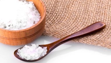 Fincanda deniz tuzu, beyaz arka planda kaşık ve çuval bezi.