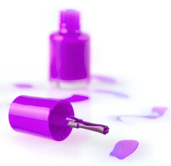 Primer plano de una botella de esmalte de uñas de color rosa y la gota sobre fondo blanco. Enfoque selectivo — Foto de Stock