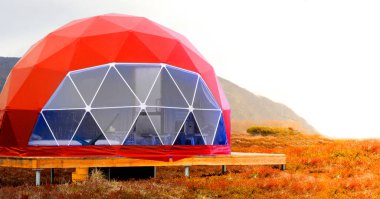 Kamçatka yarımadasında kırmızı jeo-kubbe çadırı. Rahat, kamp, glamping, tatil, tatil yaşam tarzı konsepti. Açık hava kulübesi, manzaralı arka plan