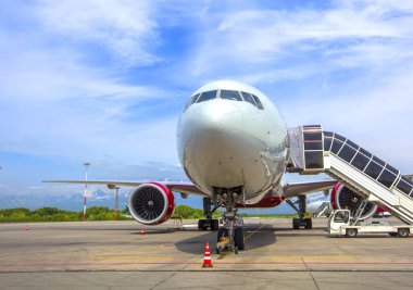 Havaalanı önlüğünün üzerinde yolcu taşıyan bir uçak.