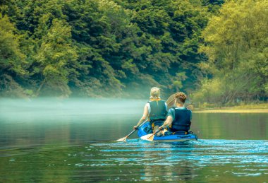 Adam ve kadın dağ gölünde sisli kanoda.