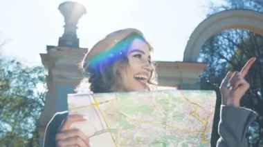 Güzel genç kız - turistler güneşli bir günde haritayla seyahat ederler. Şık bir kız, sarışın doğada bir bahar günü haritayla yürüyor. Genç bir kız turist güzel bir bahar şehrinde haritayla seyahat eder..