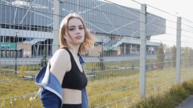 Güzel bir kız stadyumun yakınındaki sokakta spor yapmaya gider. Tarz sahibi bir kız, yaz günü sokakta egzersiz yapıyor. Kız güneşli bir yaz gününde stadyumun yakınındaki spora gider. Spor kızı spor paspası üzerinde egzersiz yapıyor.