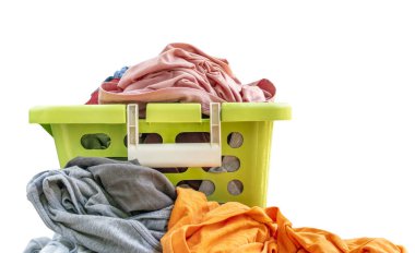 Beyaz arka planda yeşil plastik sepetteki izole kullanılmış kumaş, yeşil sepetin önü, sepetin içindeki kıyafetler ve biraz da dışarıda. Parlak renkli giysiler.