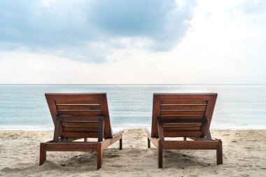 Sabahları güzel kumsalda, iki tahta güneş yatağının arka görüntüsü, geniş açık deniz ve ufuk manzarası, kopya için boş alan..