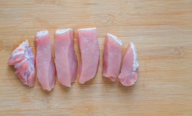 Kalın parçalara bölünmüş sağlıklı et, ahşap kesim tahtasında taze domuz eti, güzel bir şekilde dilimlenmiş domuz eti, üst görüntü. Kopyalama ve tasarım için boş alan.