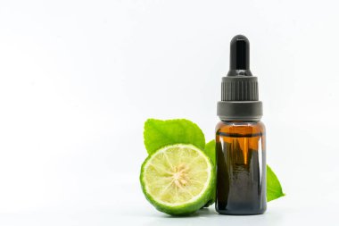 Beyaz arka planda yeşil yapraklı taze bergamot meyvesiyle küçük bir cam şişede güzel bir Bergamot esaslı yağ paketi. Etiket tasarımı için şişedeki boşluk.