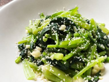 Üzerine susam tohumları ve susam yağı serpiştirilmiş bok choy salatası. Canlı yeşil yapraklar, sağlıklı, doğal ve iştah açıcı, taze malzemeler ve Asya mutfağı.