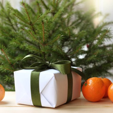 Ağacın altında yeşil kurdeleli ve mandalinalı bir hediye. Noel sürprizi