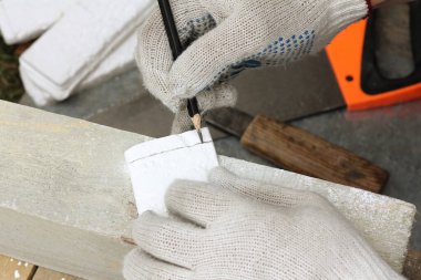 İnşaatçının elleri karonun üzerine bir kalem ile bir kesik çizgisi çizer. Dekoratif fayanslar