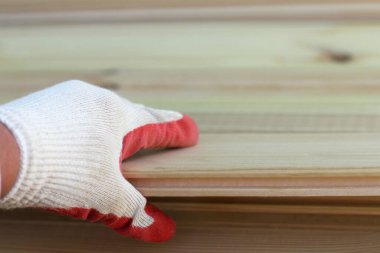 Ahşap tahta / seçme kereste taklidi tutan koruyucu eldivenlerle çalışan el.