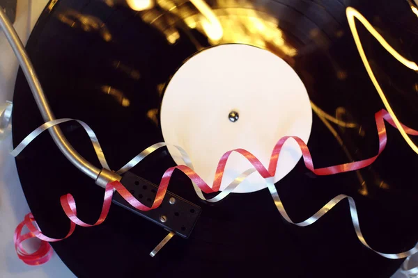 プレーヤーのトップビュー お祝いのレトロ音楽のビニールのレトロレコードの背景にあるブリュリーライトと蛇行 — ストック写真
