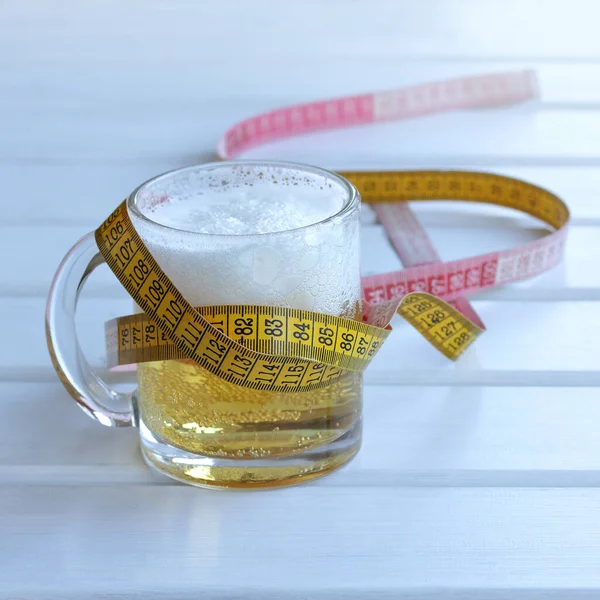 glass goblet of beer wrapped around a measuring ruler. warning about the excessive use of