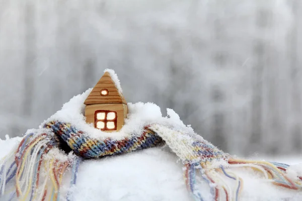 Örgü örülmüş bir eşarba sarılı ahşap bir evin penceresindeki ışık, karla kaplı bir manzaranın arka planına karşı. Samimi sevgili evim.
