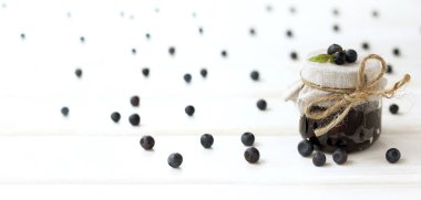 Uzun bir masada doğal yabanmersini reçeli kavanozu, ön manzara. Tatlı yabanmersinli tatlı