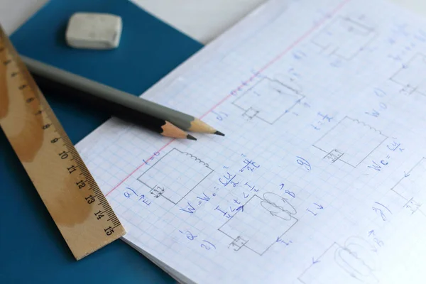 ruler and pencils on an open physics notebook. difficult task