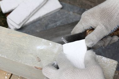 Bir işçi alçı tuğlaların kenarlarını temizler. hazırlayıcı yenileme çalışmaları