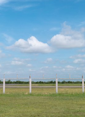 Mavi gökyüzü ve beyaz yumuşak bulutları olan çim tarlası ve çit alanının arka planı.