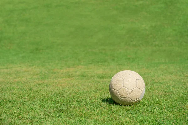 Old soccer ball on green grass of soccer field. Vintage football.