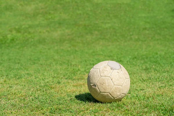 Old soccer ball on green grass of soccer field. Vintage football.