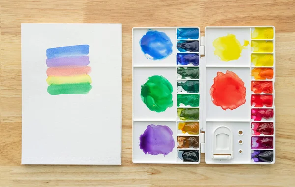 Watercolor paints set in white palette with white paper for background. Colorful multicolored aquarelle paints in paint box.