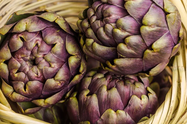 Świeżych karczochów fioletowy w tło zbliżenie kosz Wiklinowy — Zdjęcie stockowe