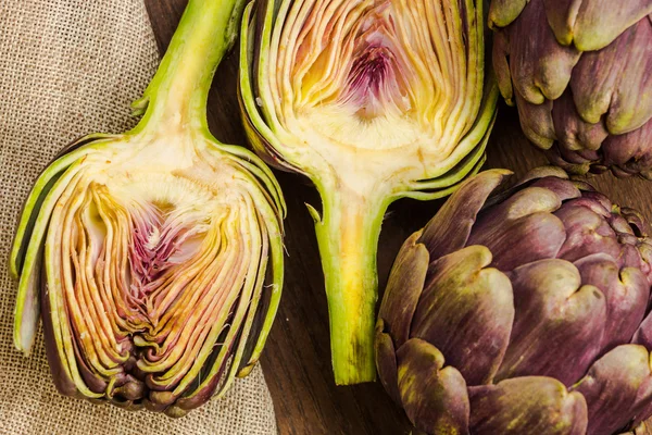 Fresh cut purple artichokes close up background — стоковое фото